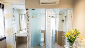 Un baño moderno con mampara de vidrio, un lavamanos, inodoro y zona de ducha.