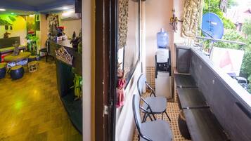 A small, compact room with a wooden floor, a water dispenser, a chair, and a small table.