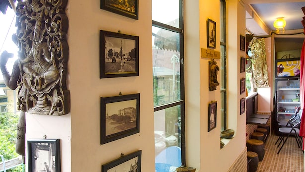 A hallway with framed pictures on the walls, a window, and a patterned floor. - Shannkalay Hostel (Yangon)