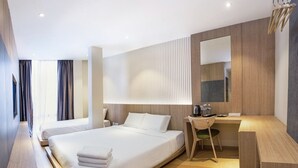 A modern hotel room with two beds, a desk, and a large mirror.