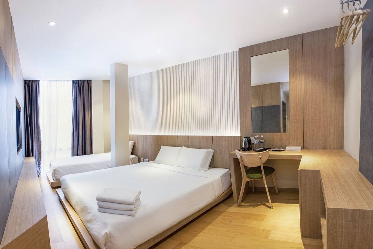 A modern hotel room with two beds, a desk, and a large mirror.