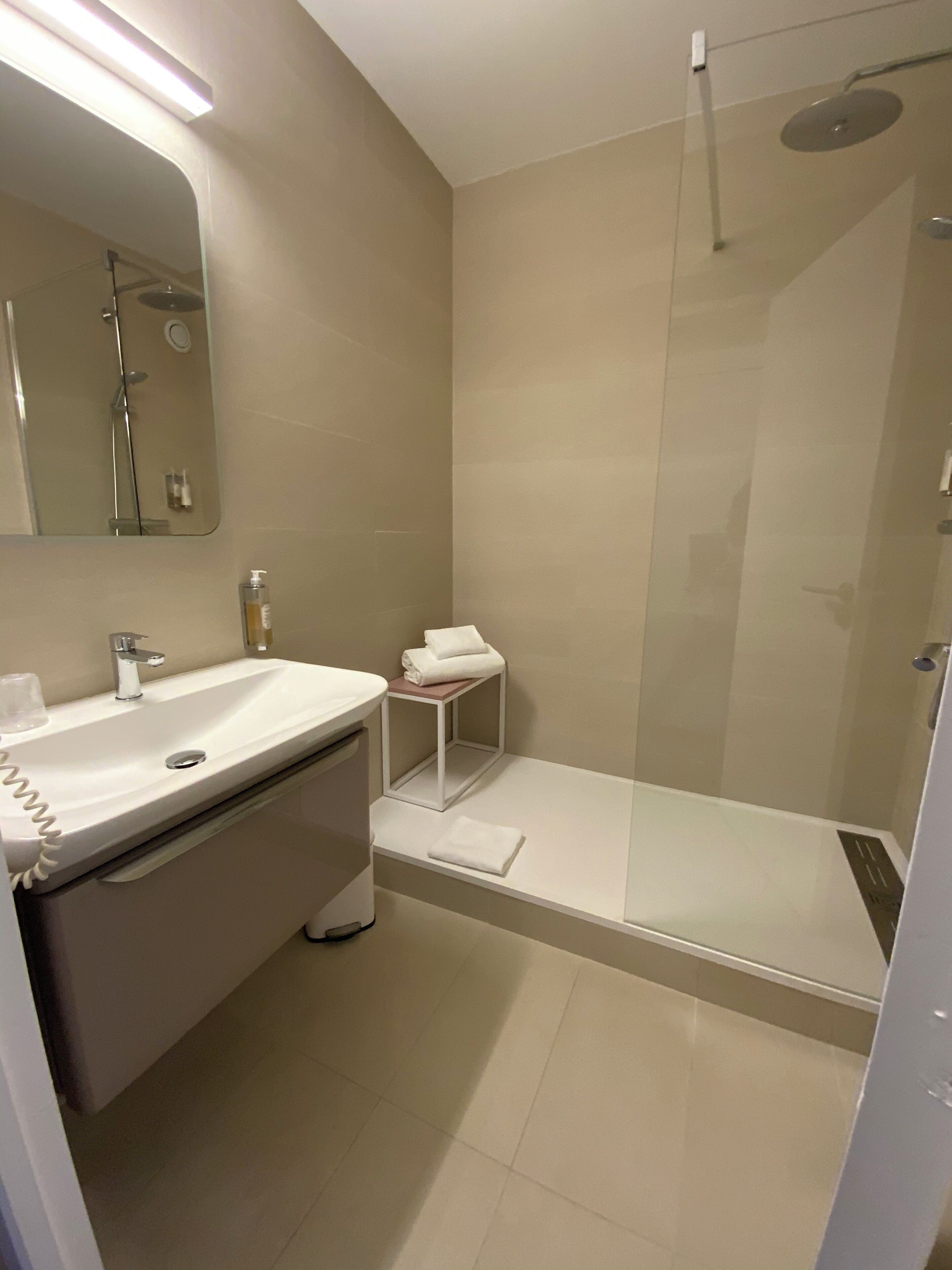 A modern bathroom with a sink, mirror, and shower.