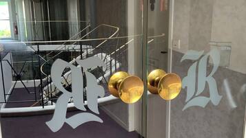 A modern interior with a glass door featuring large decorative letters and a reflection of a staircase.