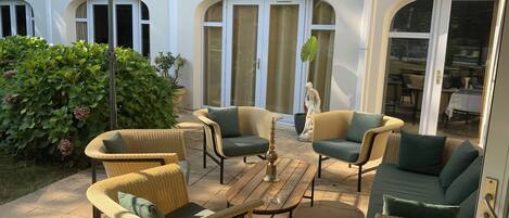 Un patio al aire libre con mobiliario de mimbre, una mesa de madera y una estatua.