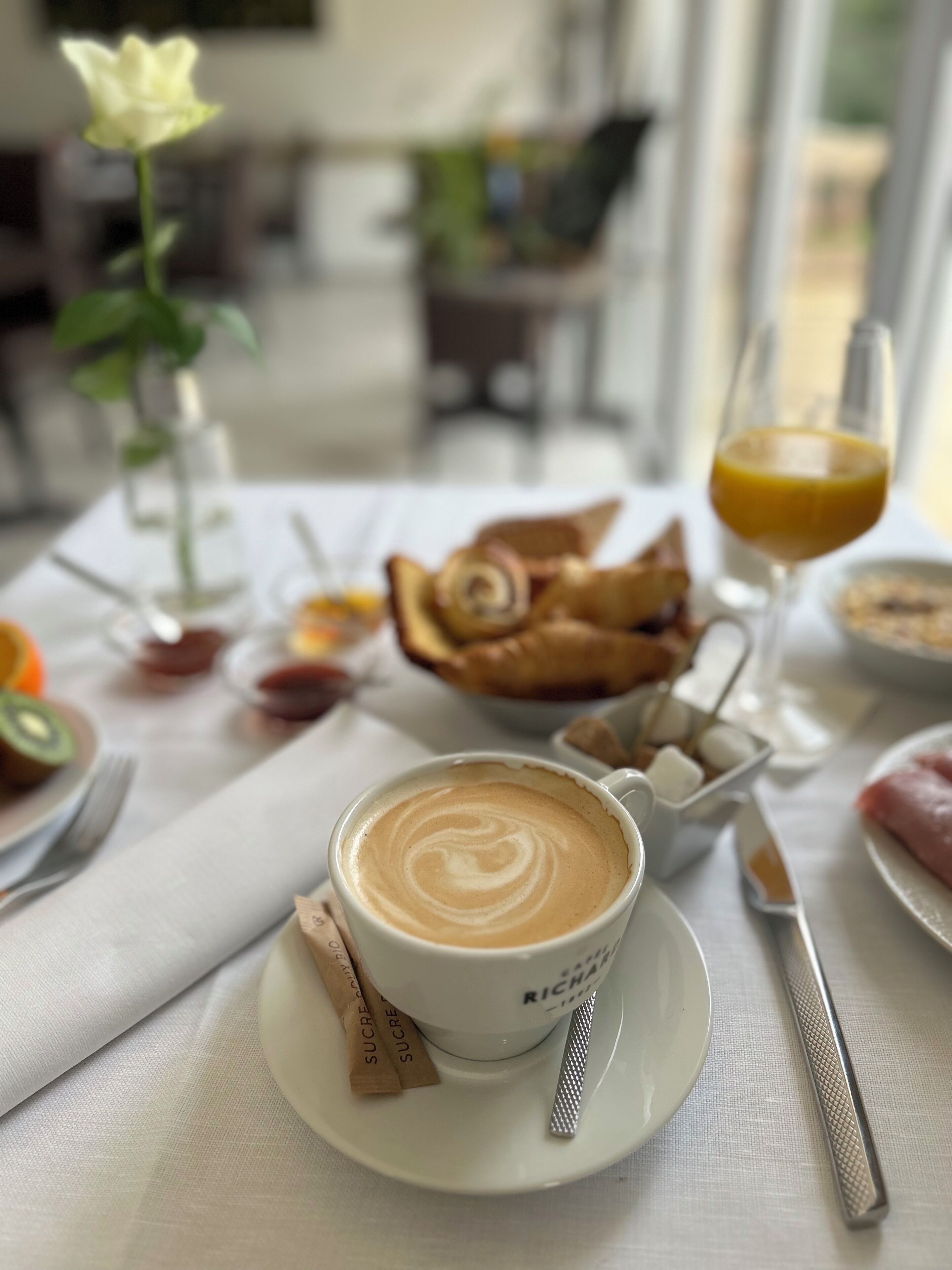 Et bord med en kop kaffe, et glas appelsinjuice og kager.