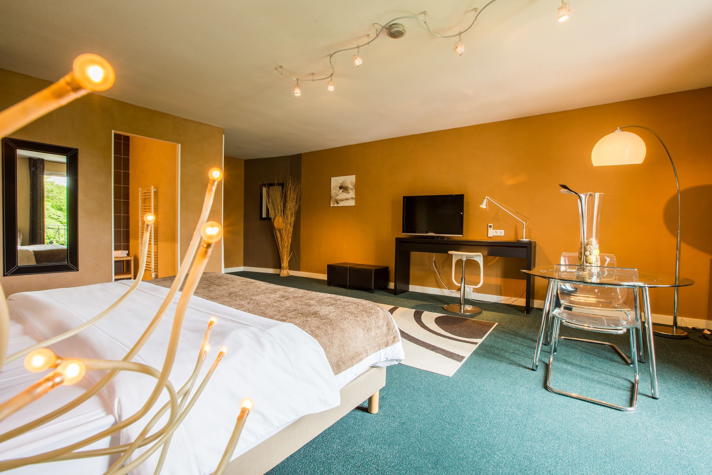 Una habitación de hotel moderna con cama, escritorio, silla, televisor y luces decorativas.