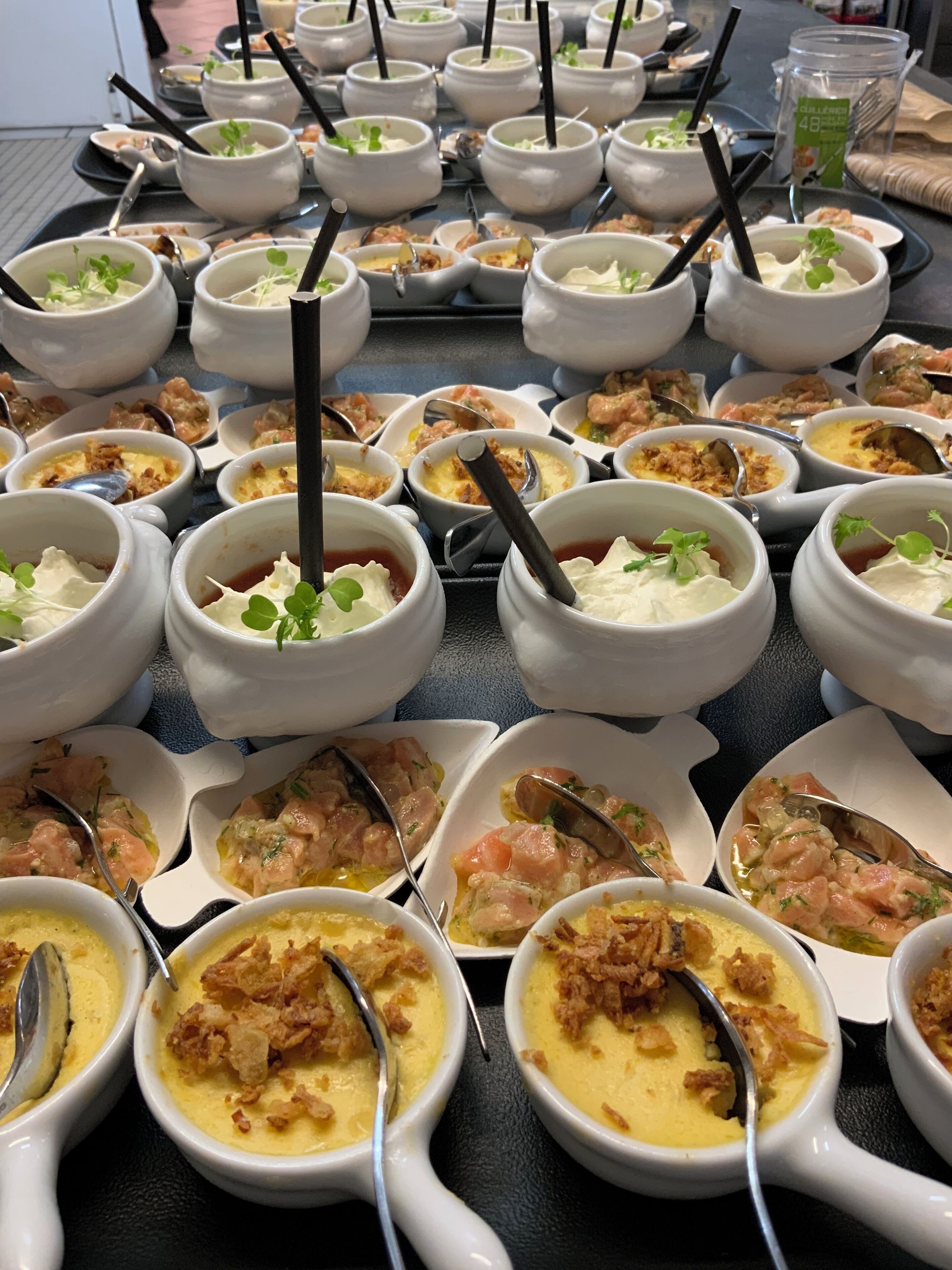 Una mesa de buffet con diversos platos en cuencos de cerámica blanca, algunos con adornos y otros con mariscos.
