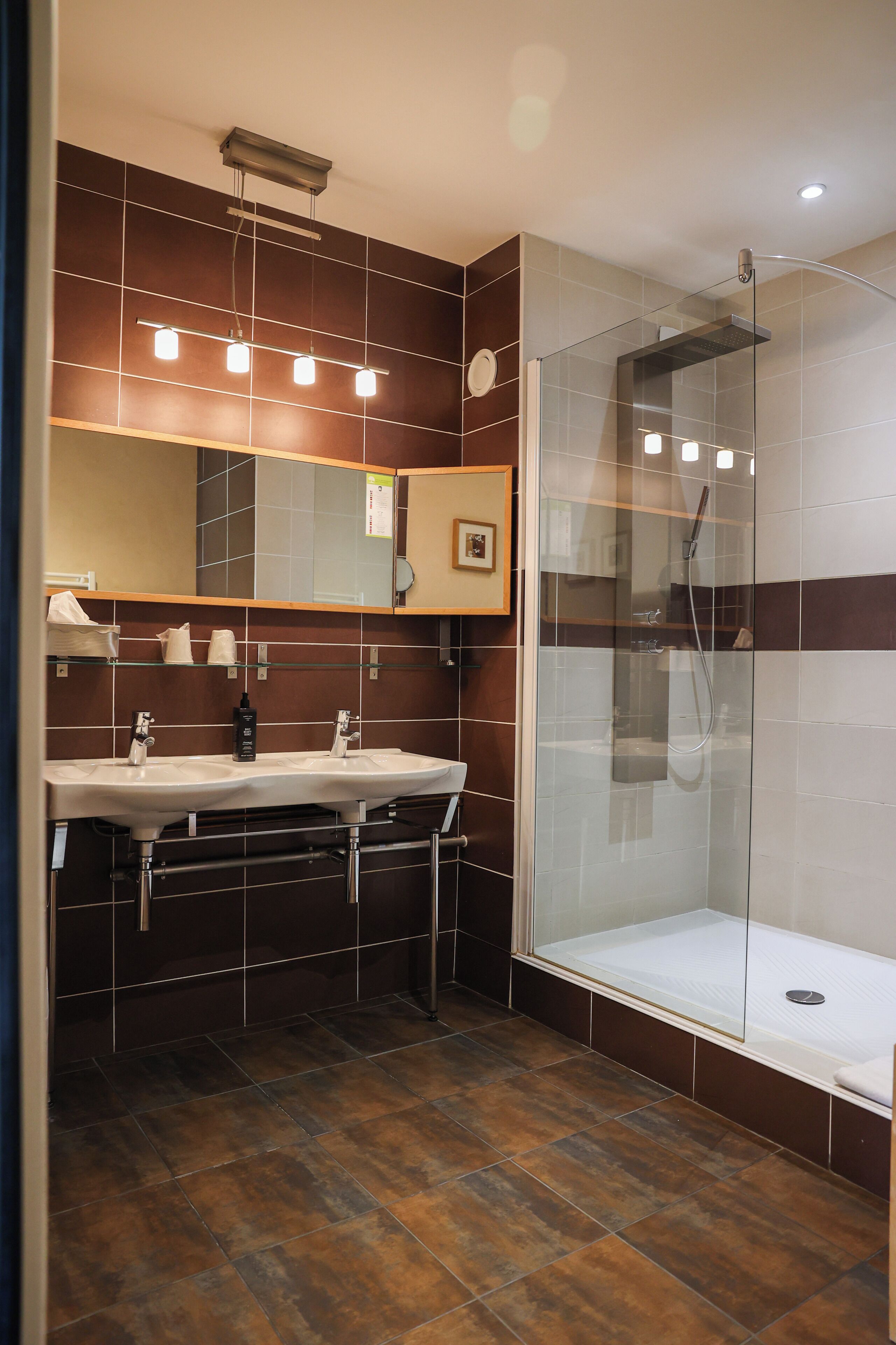 Une salle de bain moderne avec une douche à parois de verre, un meuble-lavabo à deux vasques et un grand miroir.