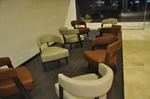 Uma área de estar com várias cadeiras e um banco, dispostos em semicírculo.
