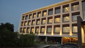 A modern hotel building with multiple floors, large windows, and a well-lit entrance. - Pride Biznotel Alkapuri (Savli)