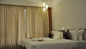 A hotel room with a large bed, beige curtains, and two pendant lights. - Pride Biznotel Alkapuri (Savli)