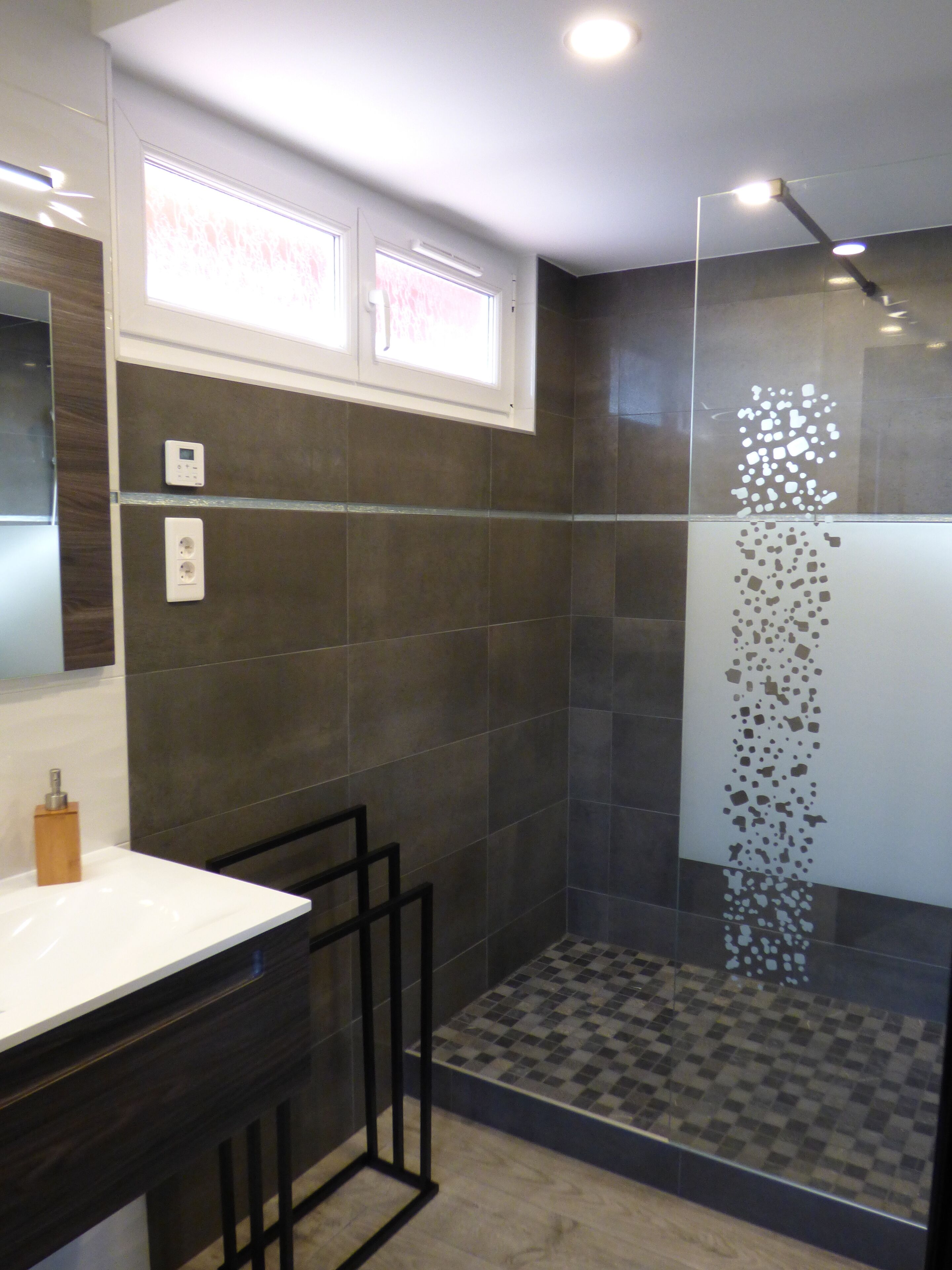 A modern bathroom with a shower, a sink, and a mirror.