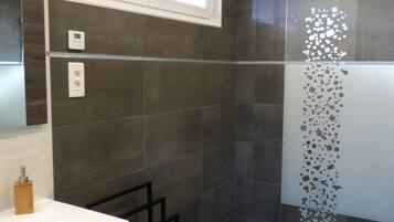 A modern bathroom with a shower, a sink, and a mirror.