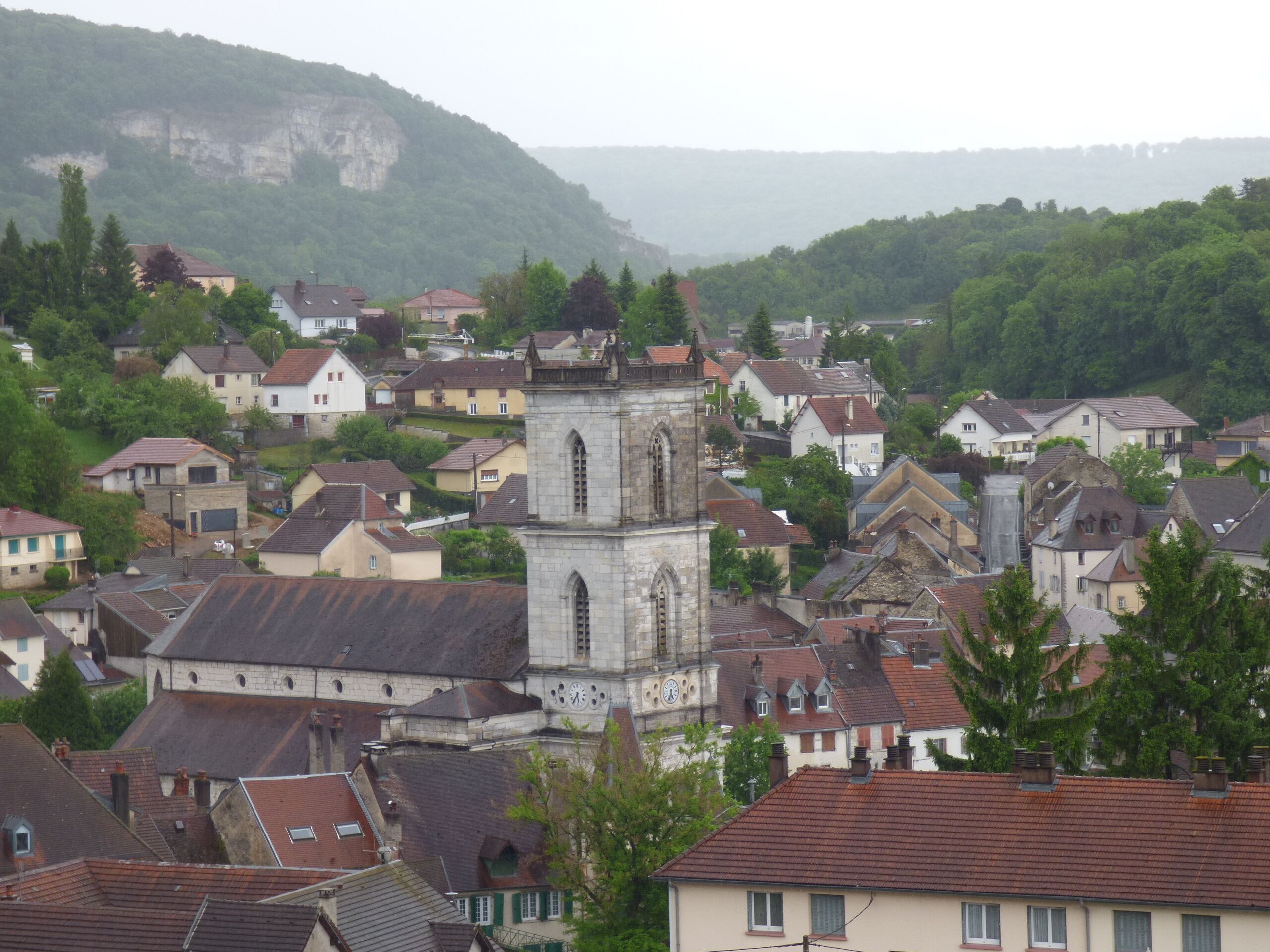 A town with a prominent church tower, surrounded by residential buildings and greenery.