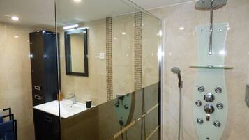 Un baño moderno con ducha de vidrio, lavamanos y espejo.