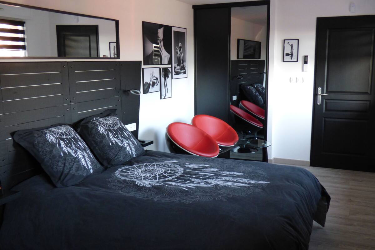 Un dormitorio con cama, espejo y puerta.