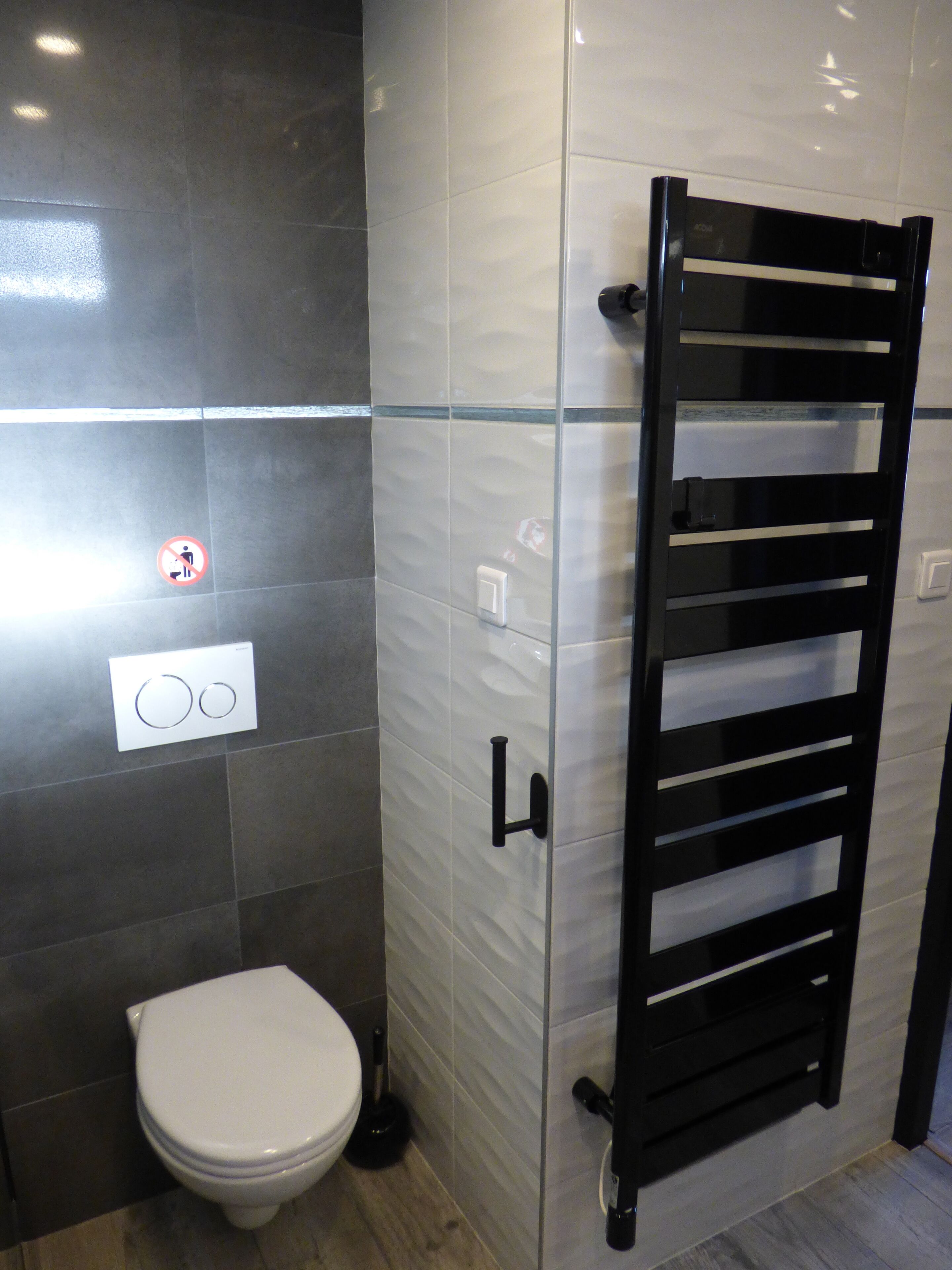 Ein modernes Badezimmer mit Toilette, einem Händetrockner und einem Handtuchhalter.