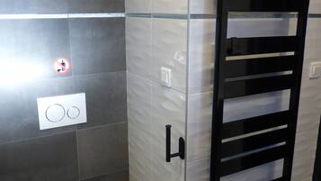 Ein modernes Badezimmer mit Toilette, einem Händetrockner und einem Handtuchhalter.