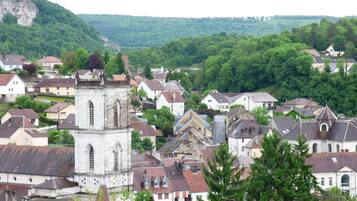 Eine historische Stadt mit einem markanten Glockenturm, umgeben von Wohnhäusern und üppiger Vegetation.