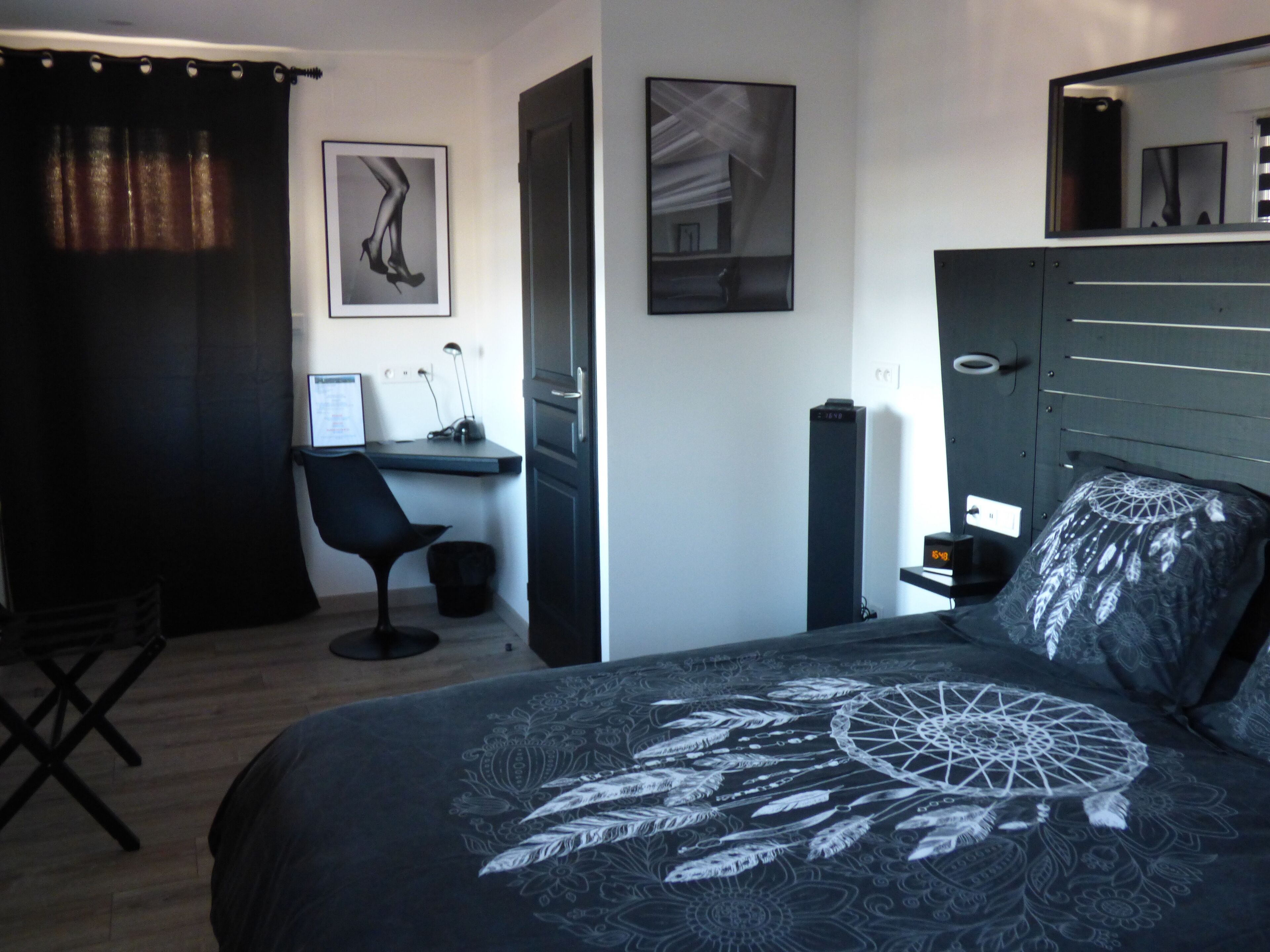 Une chambre à coucher avec un lit, un bureau et une chaise. Deux tableaux encadrés sont accrochés au mur.