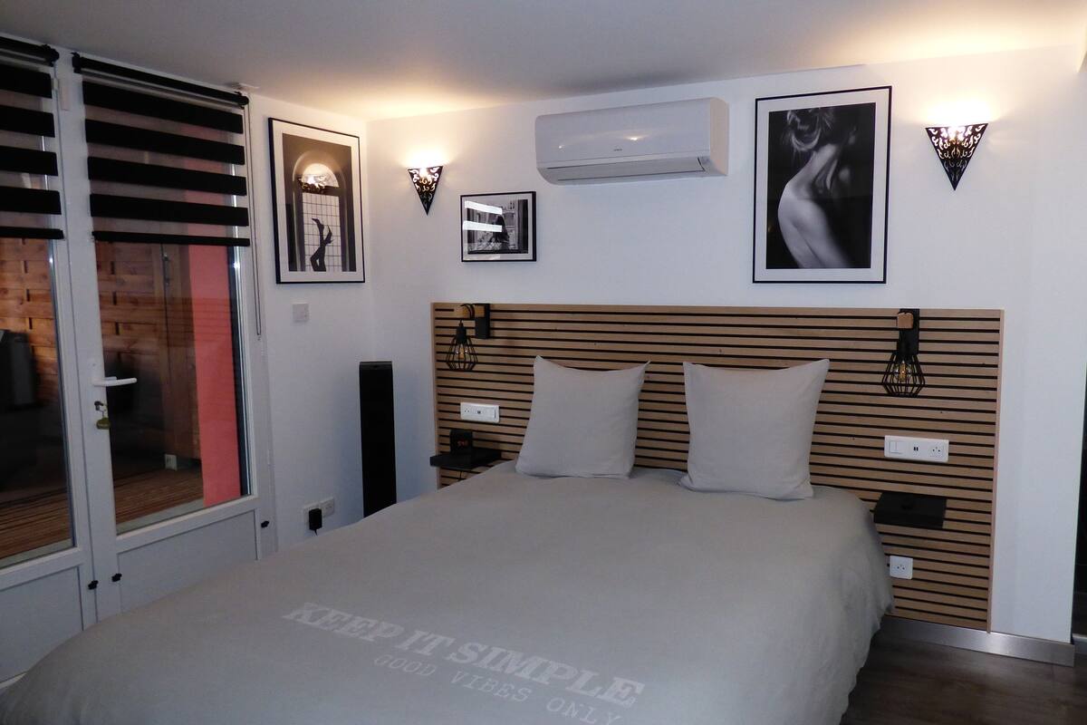 Un dormitorio moderno con una cama grande, cabecera de madera y una puerta corrediza de vidrio que da a un balcón.
