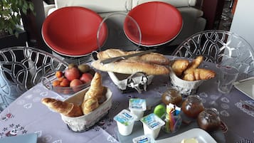Tafel gedekt met brood, fruit, gebak en toevoegingen.