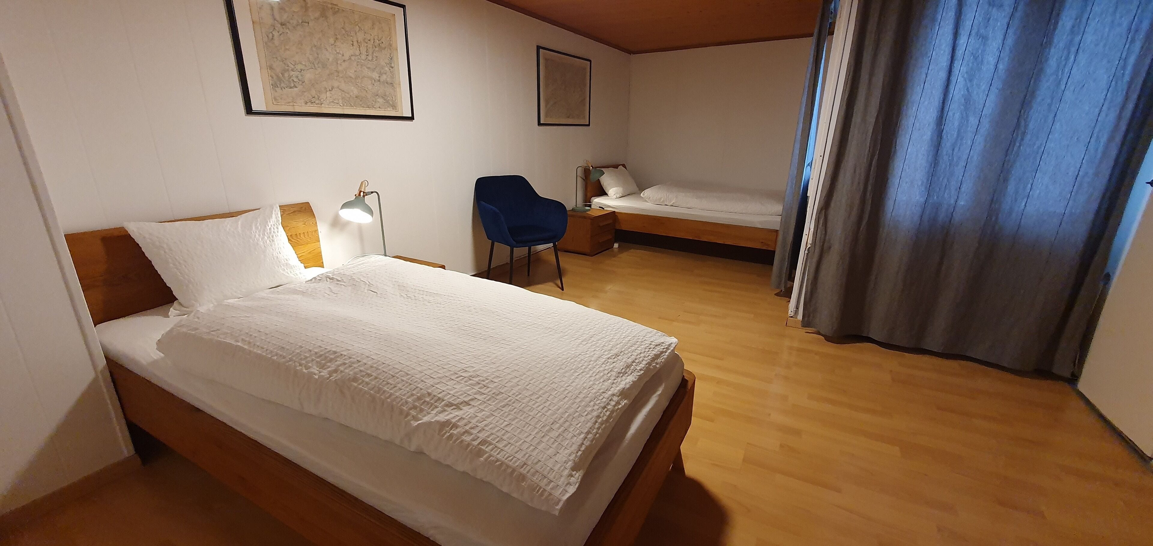 A bedroom with a large bed, a smaller bed, a chair, and a desk.
