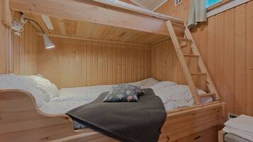 Una cama litera de madera con escalera, un escritorio pequeño y una ventana con vistas.
