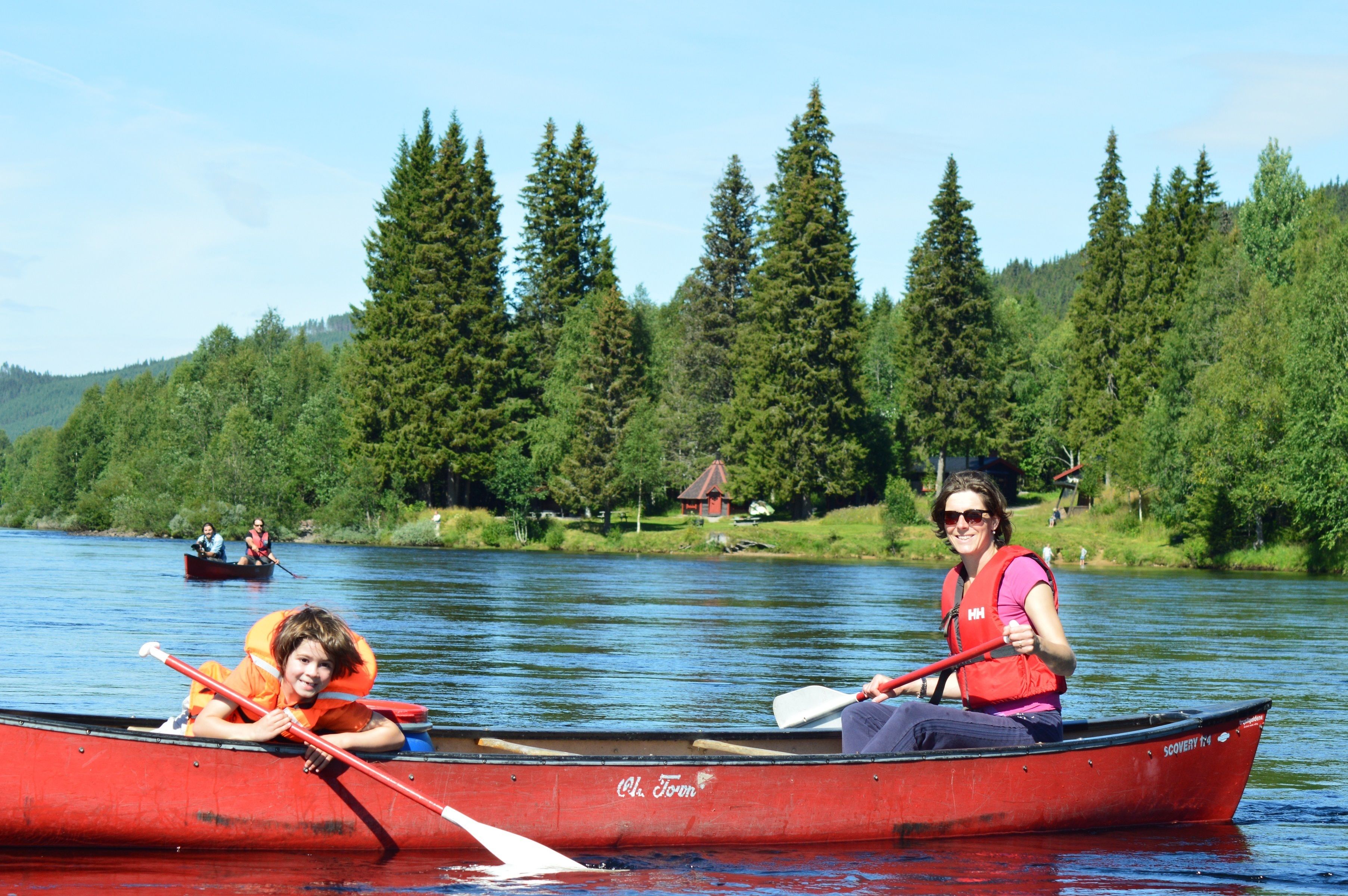Un canoa rosso su un lago calmo, con una fitta foresta sullo sfondo.