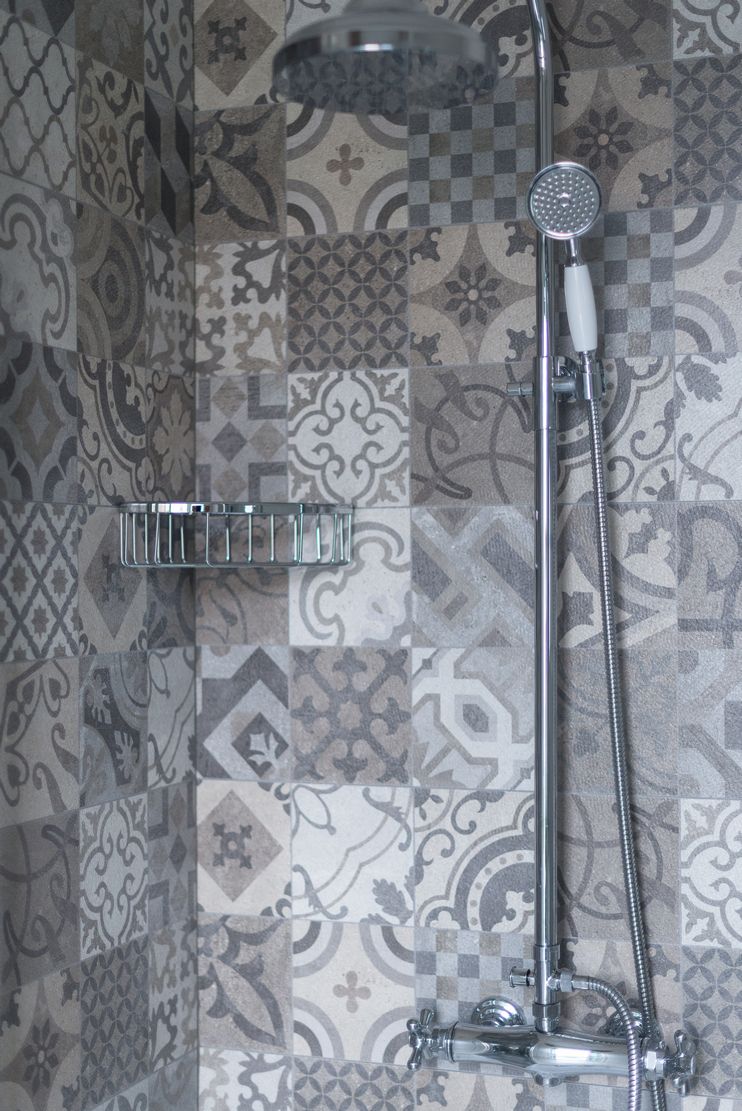 Une douche équipée d’un pommeau de douche à main et d’un robinet fixé au mur.