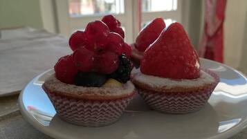 Two cupcakes with fruit toppings on a white plate.