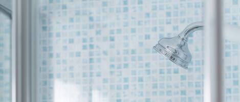 A bathroom with a shower head and a tiled wall.