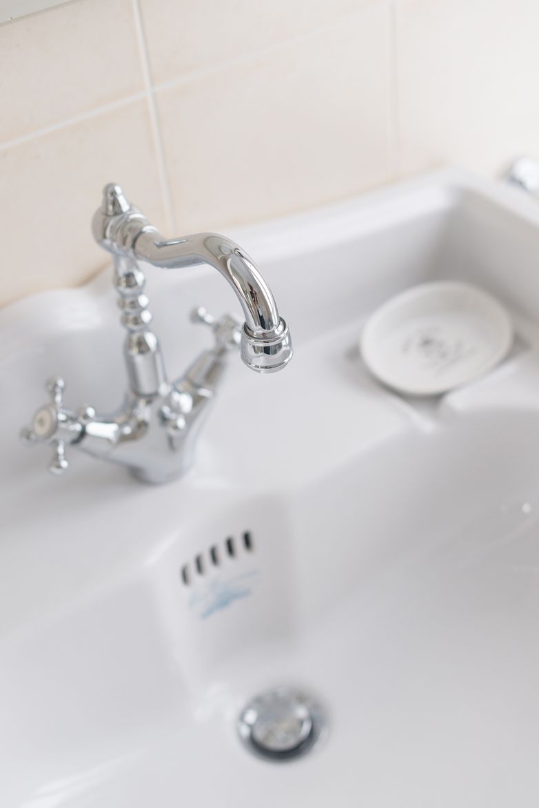 Un baño moderno con un grifo cromado, un jabonera y un lavabo blanco.