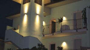 A multi-story building with a prominent tower-like structure, balconies with railings, and exterior lighting. -  Gruppo Luxe Domus (Vigevano)