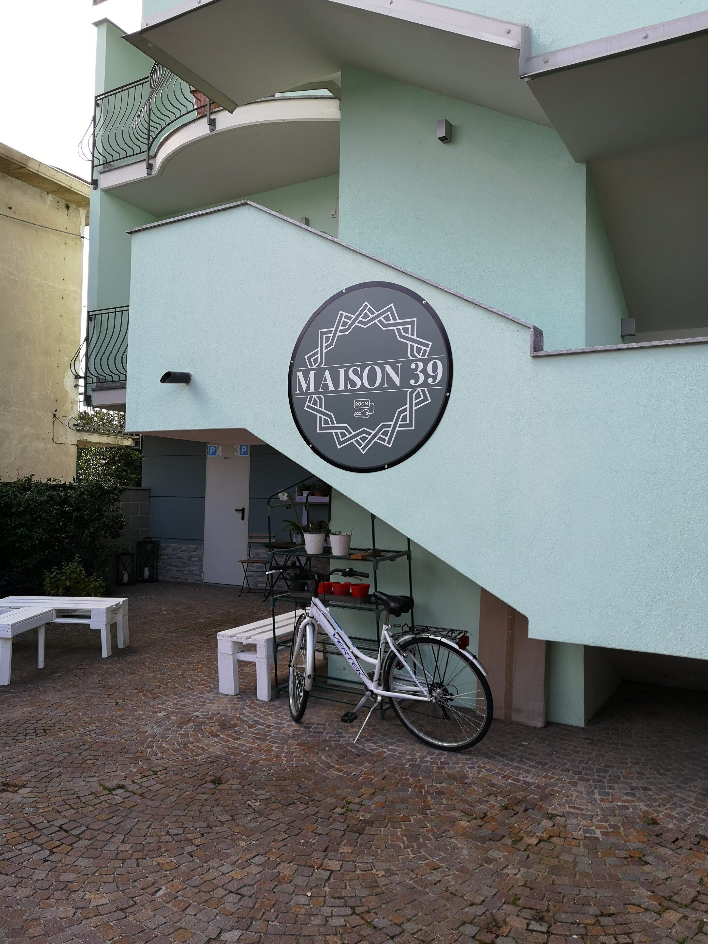 Un edificio con un cartel que dice "MAISON 39" y una bicicleta estacionada adelante.