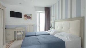 A hotel room with two beds, a desk, a chair, a TV, and a window with curtains. -  Gruppo Luxe Domus (Vigevano)