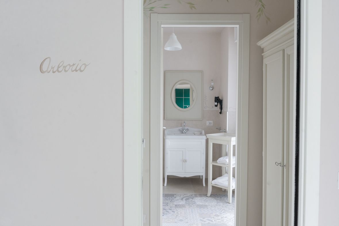 Un pasillo que conduce a un baño con tocador blanco, espejo y lavabo.