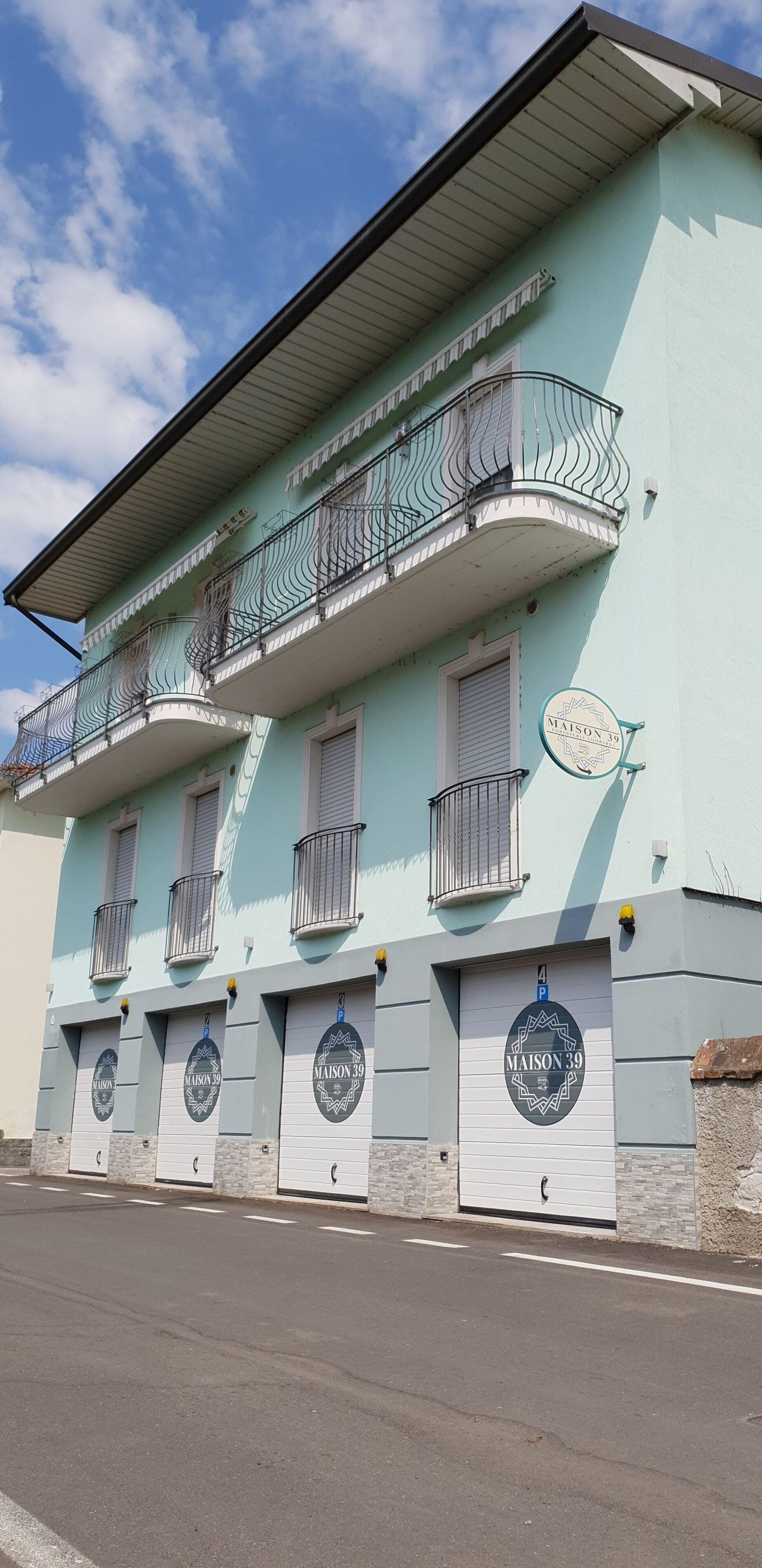 A building with multiple balconies, a garage door, and a sign indicating 'MAISON 39'.