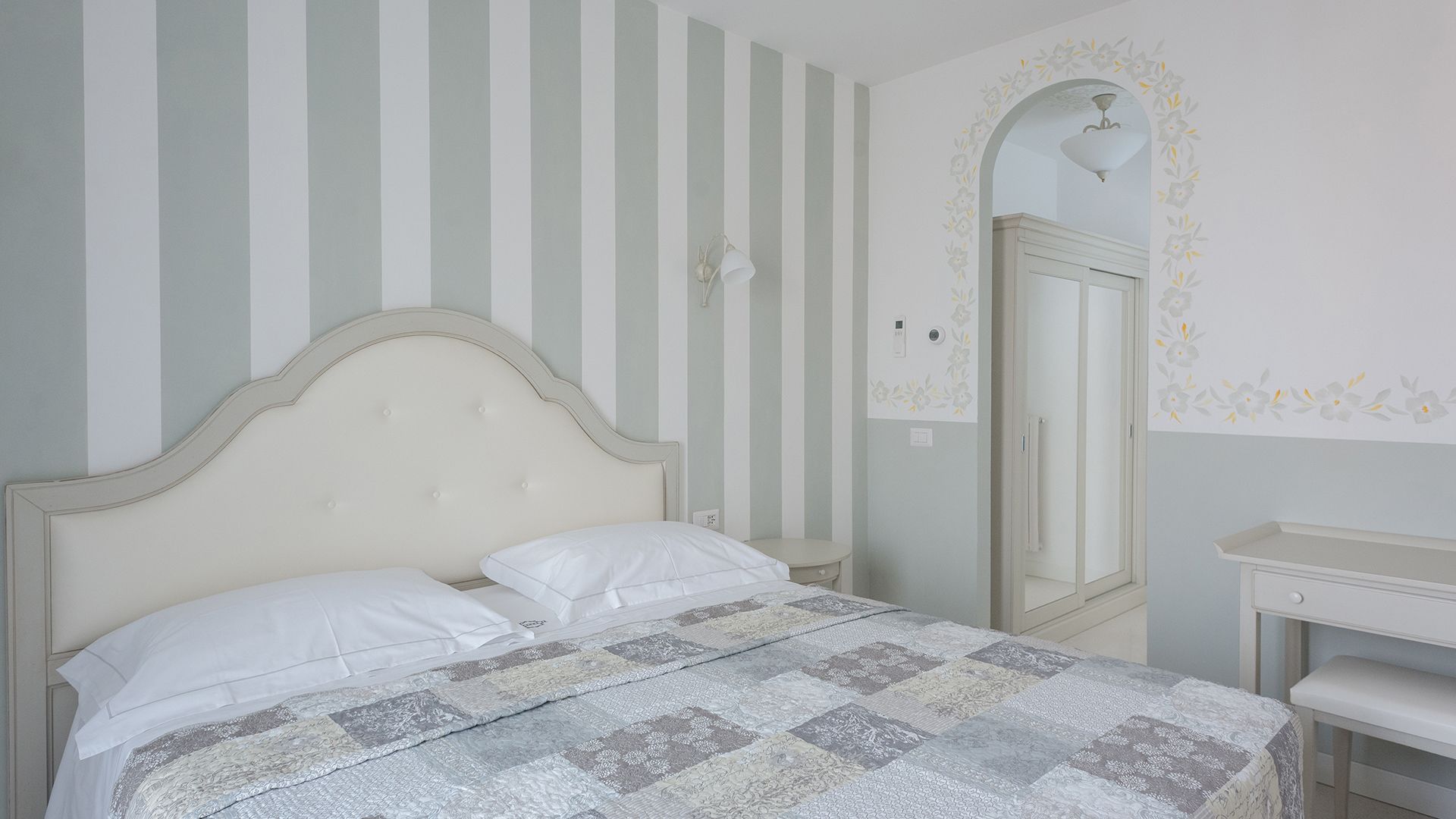 Une chambre à coucher avec un lit, une table de chevet, une commode et un miroir.