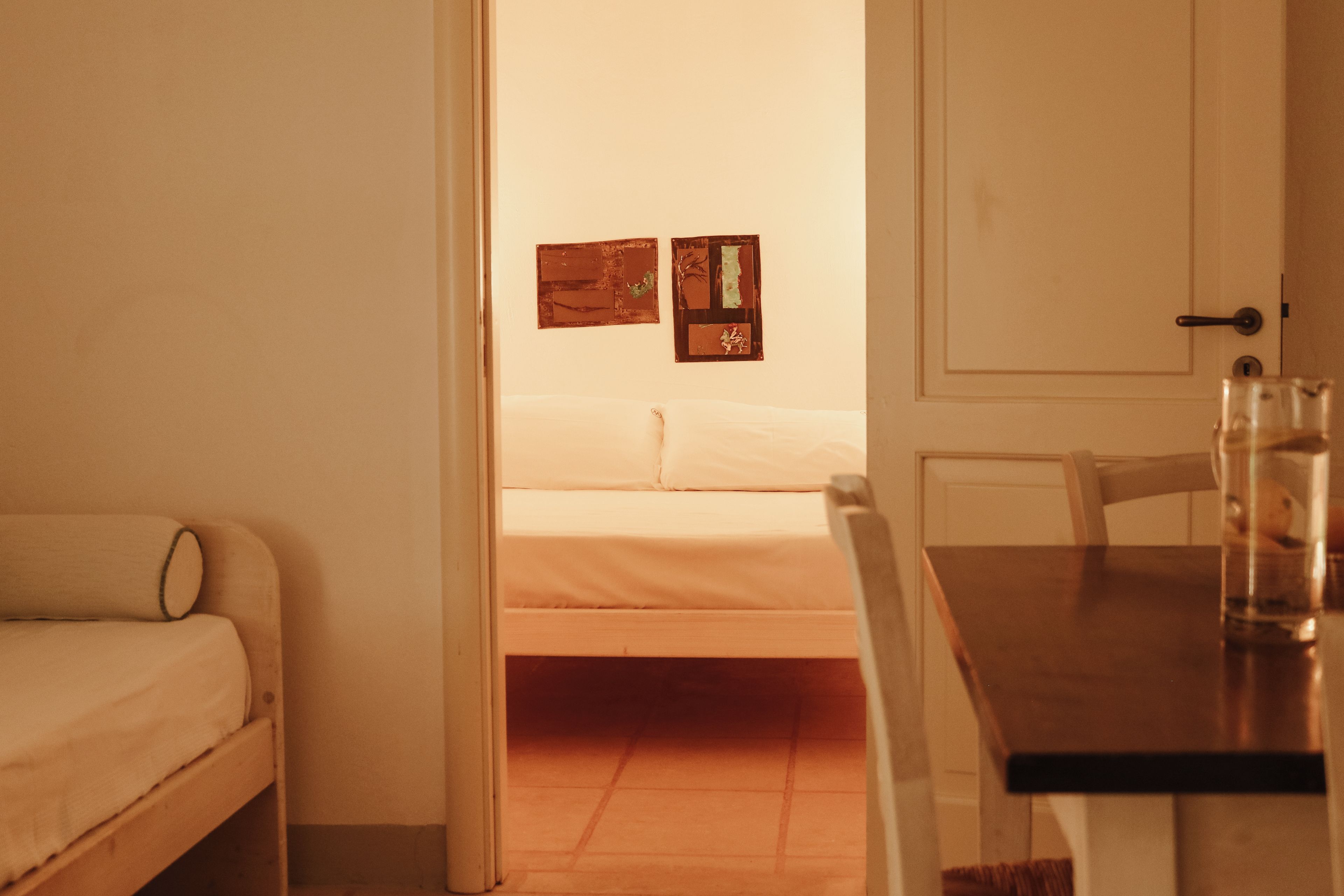 A room with a bed, a table with a glass, and a door.