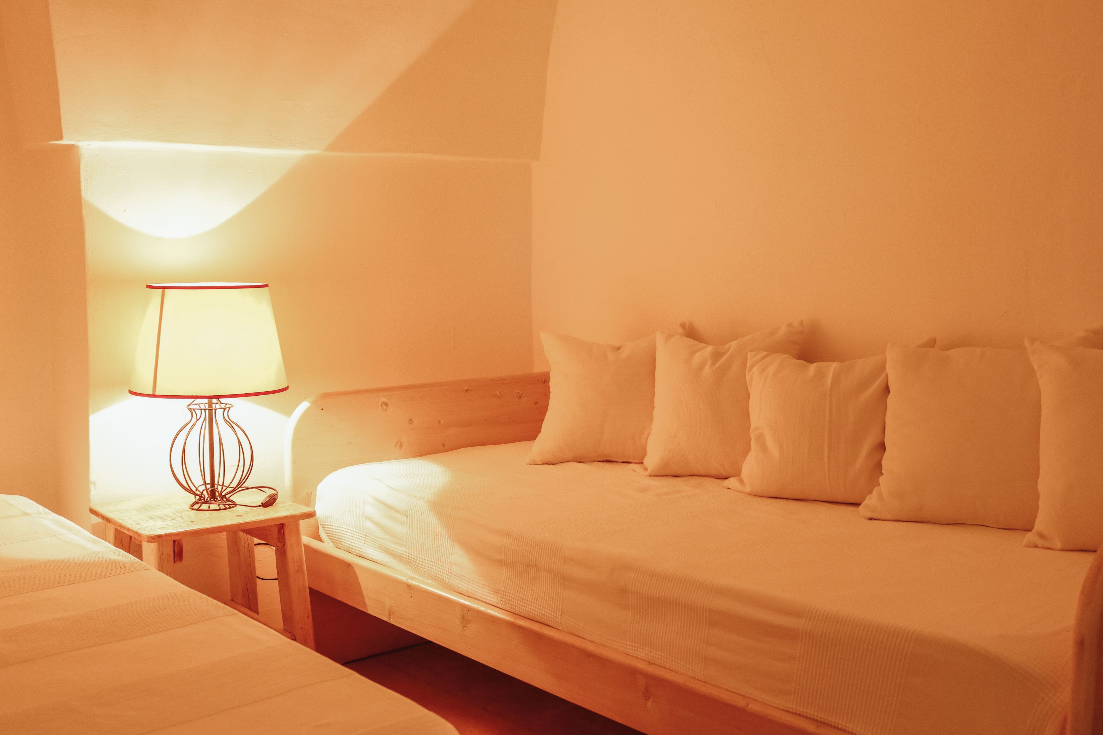 Ein Einzelbett mit Holz Kopfteil und weißer Bettwäsche in einem Zimmer mit geneigter Decke.