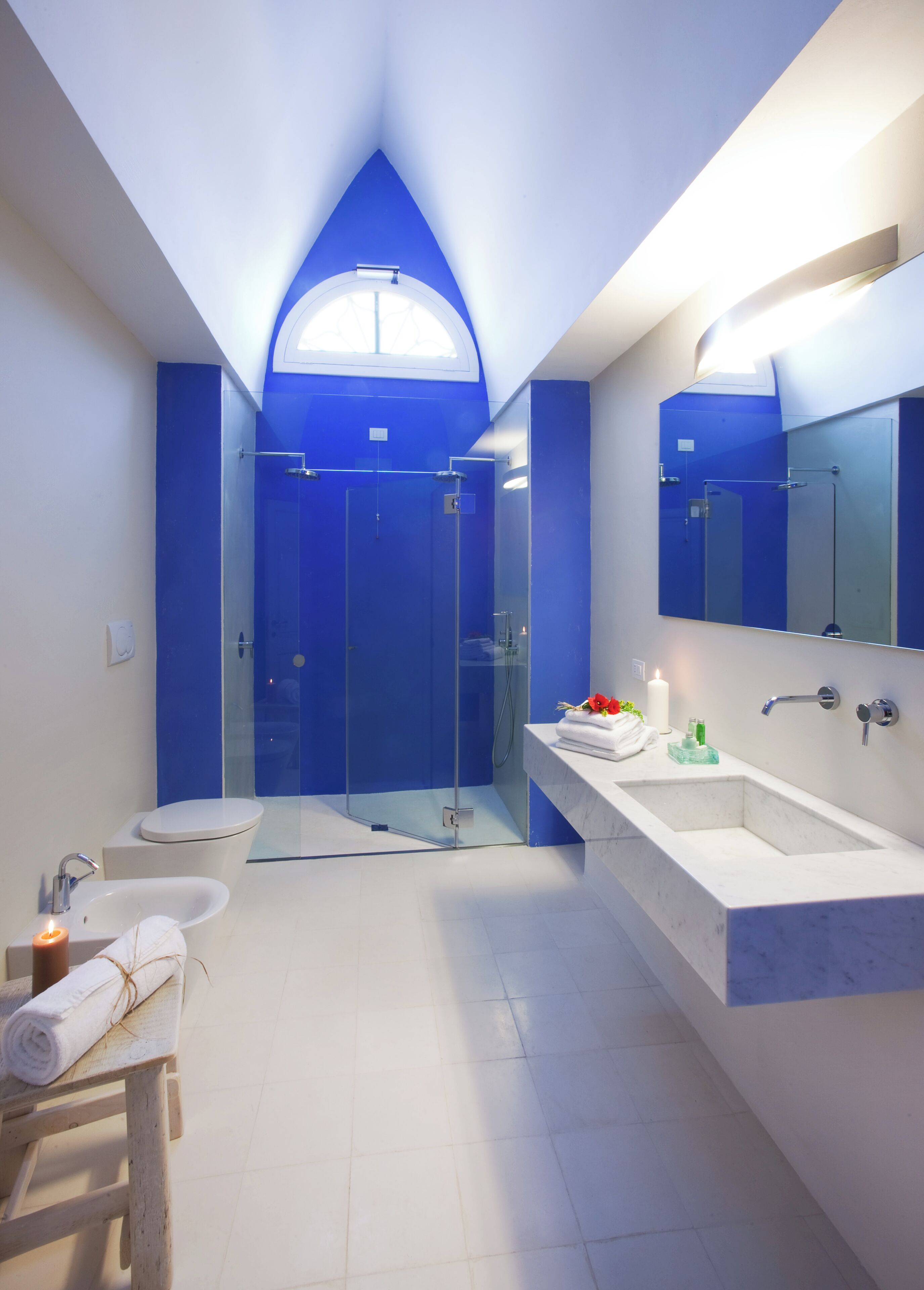 Une salle de bain moderne avec une douche à parois de verre, un grand miroir et un meuble-lavabo.