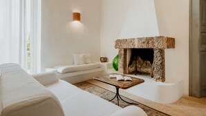 A modern living room with a white sofa, a fireplace, and a small table with a book. - Masseria Li Foggi (Gallipoli)
