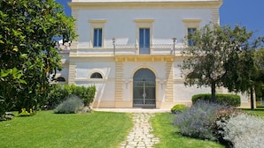 A two-story building with a central entrance, arched doorway, and a balcony with railings. - Masseria Li Foggi (Gallipoli)