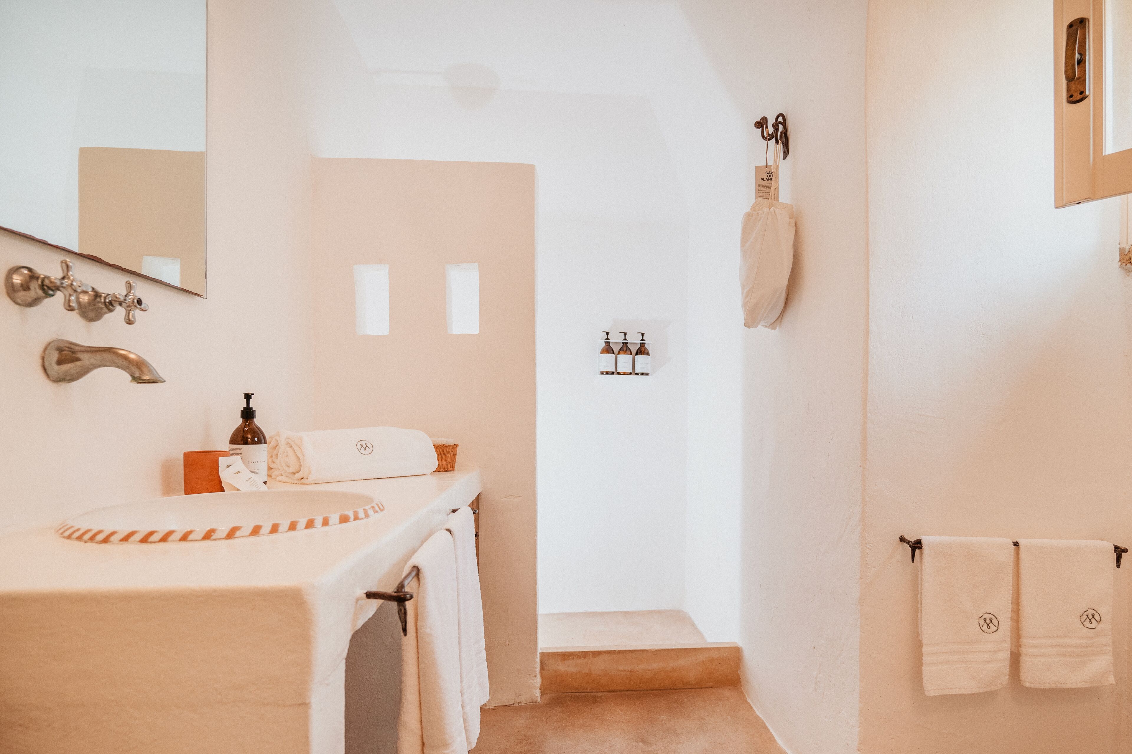 A bathroom with a sink, mirror, towel rack, and a shower area.