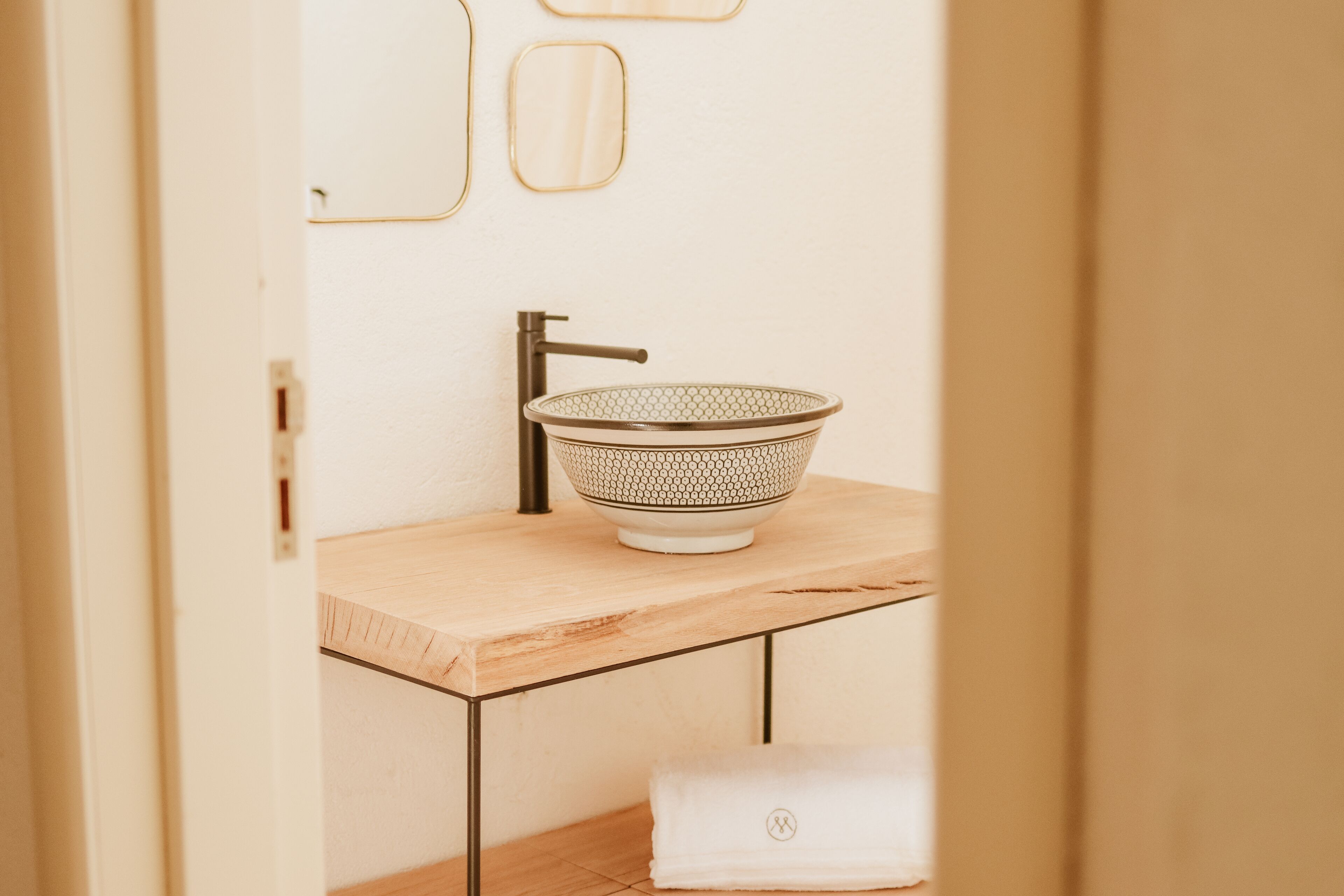 Ein Badezimmer mit einem Holzkosmetikschrank, einem Waschbecken aus Glas und einem Handtuch auf dem Boden.