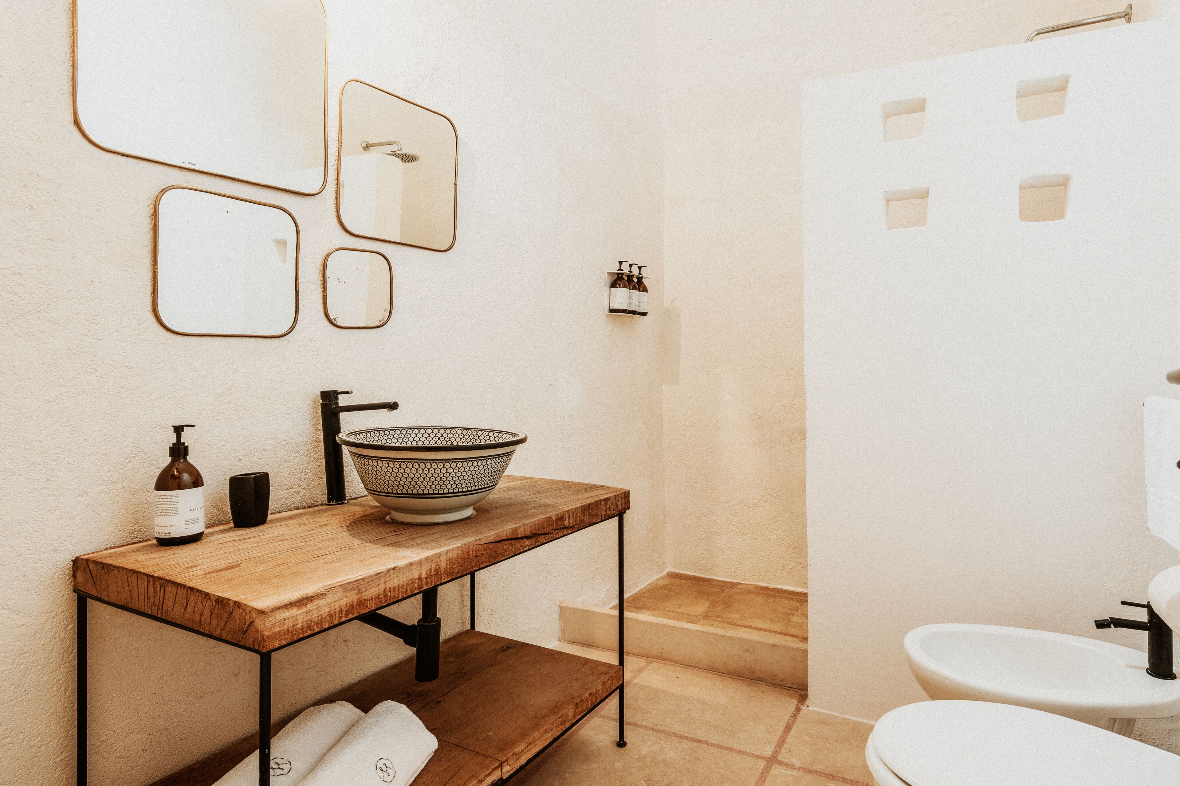 A bathroom with a wooden vanity, a sink, a mirror, a shower, and a toilet.