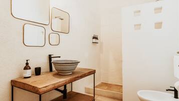 Une salle de bain avec un meuble-lavabo en bois, un évier, un miroir, une douche et des toilettes.