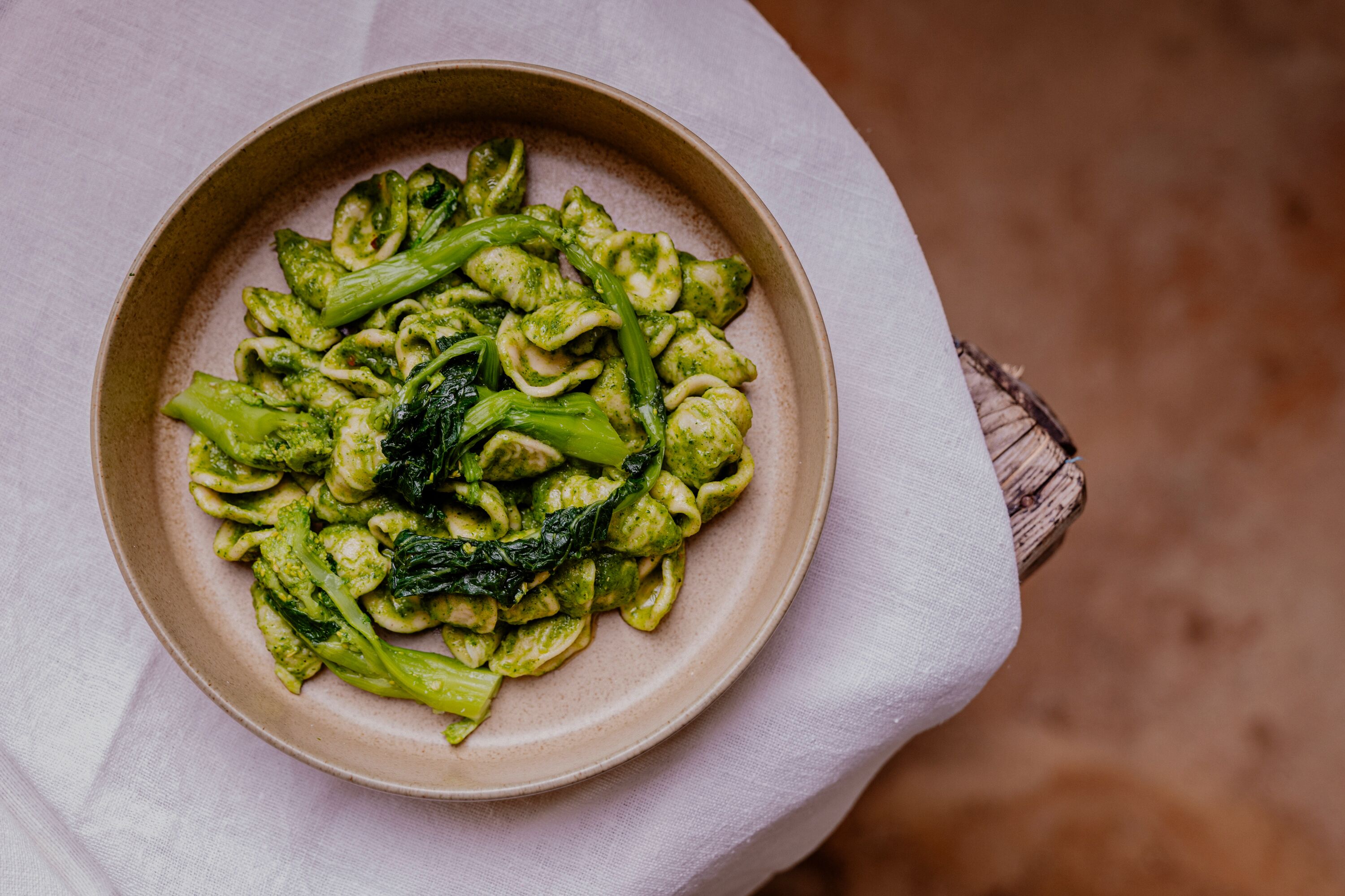 A bowl of green vegetable stir-fry on a beige plate.