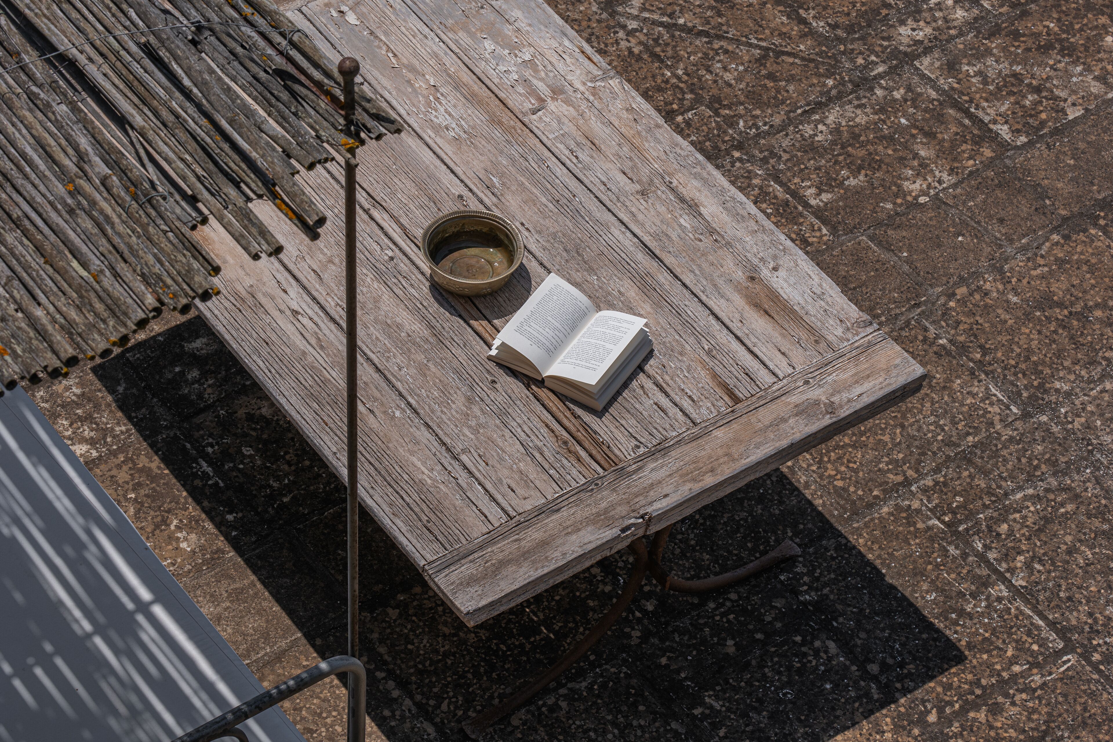 Una mesa de madera con un libro y un cuenco pequeño encima.